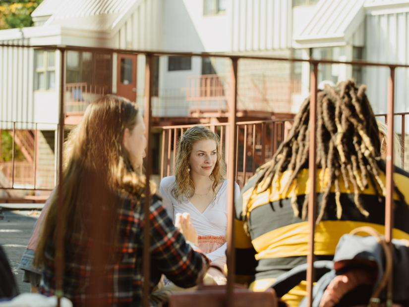 image of a group of people on campus sitting together with the focus on one girl